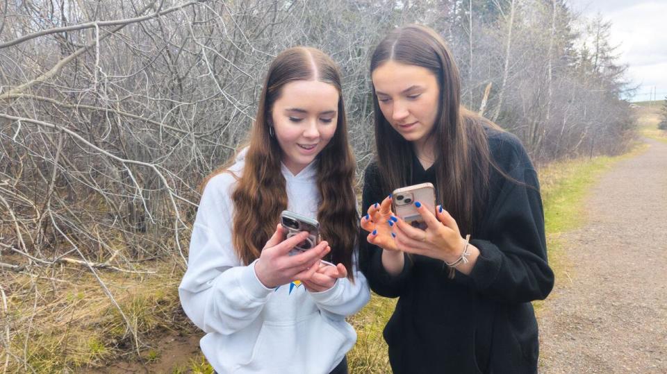 Students Caitlin McGuire (left) and Lauryn Matheson look at some of the photos on the iNaturalist app. 