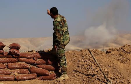 A Kurdish Peshmerga soldier who is stationed between two front lines gestures as a smoke rises near Bashiqa, east of Mosul, Iraq October 29, 2016. REUTERS/Zohra Bensemra