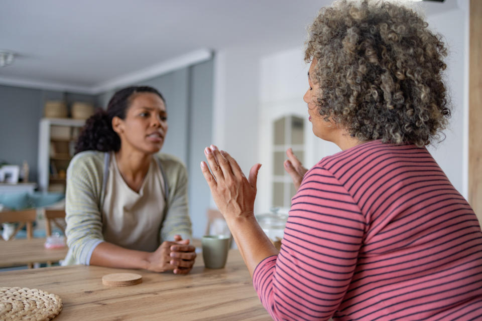 Two women engaged in a conversation while sitting in a kitchen