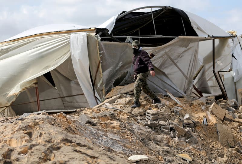 A Palestinian militant walks as he surveys an Islamic Jihad site that was targeted in an Israeli air strike in the southern Gaza Strip