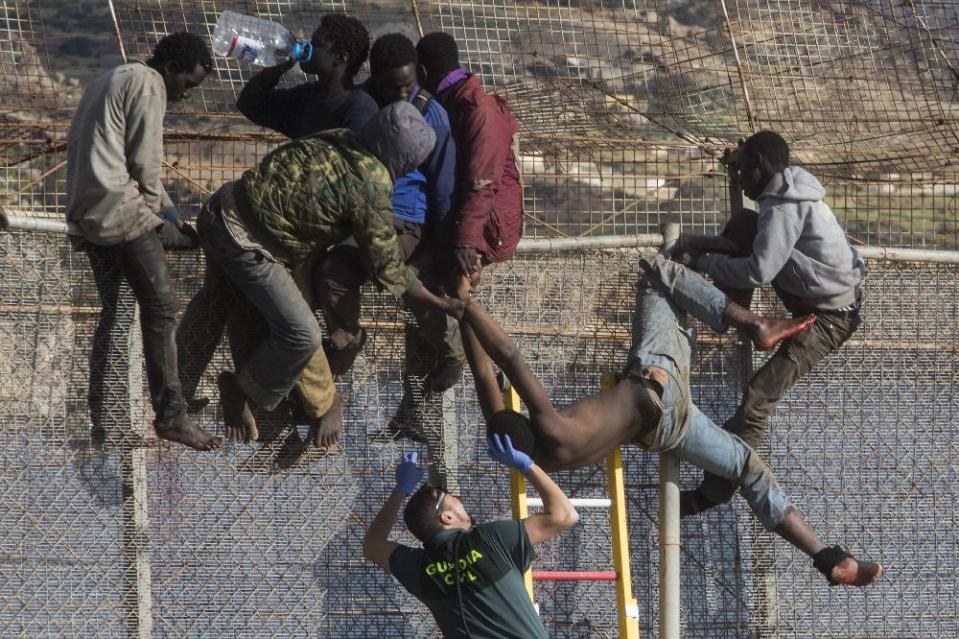 A sub-Saharan migrant is helped by a Spanish Guardia Civil officer after he fainted on top of a metallic fence that divides Morocco and the Spanish enclave of Melilla, Thursday, April 3, 2014. Spanish and Moroccan police have thwarted a fresh attempt by dozens of African migrants to try to scale border fences to enter the Spanish enclave of Melilla. Thousands of sub-Saharan migrants seeking a better life in Europe are living illegally in Morocco and regularly try to enter Melilla in the hope of later making it to mainland Spain. (AP Photo/Santi Palacios)