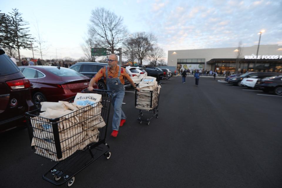 Rick Marquardt with Whole Foods Market regional marketing team brings over two carts full of bags to give to the first several hundred customers as part of a promotion of their newly opened store.