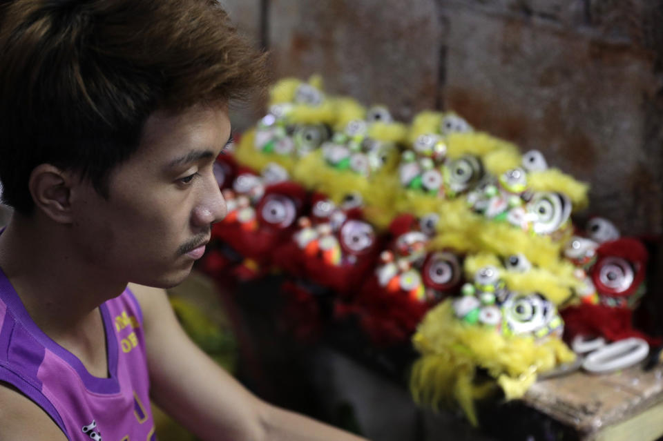 Jhayvee Sicat rests as they rush orders of miniature lion heads as members of a dragon and lion dance group seek other ways to earn a living at a creekside slum in Manila's Chinatown, Binondo, Philippines on Feb. 8, 2021. The Dragon and Lion dancers won't be performing this year after the Manila city government banned the dragon dance, street parties, stage shows or any other similar activities during celebrations for Chinese New Year due to COVID-19 restrictions leaving several businesses without income as the country grapples to start vaccination this month. (AP Photo/Aaron Favila)
