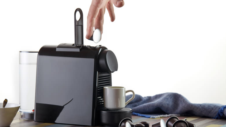 person lowering coffee pod into espresso machine