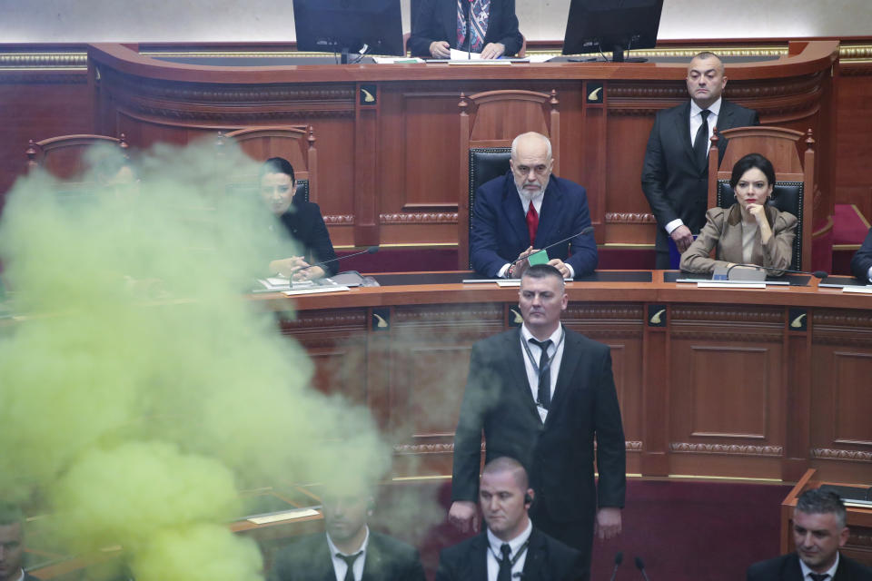 Albanian Prime Minister Edi Rama center, watches as democratic lawmakers use smoke and flares to try and block the parliament session in Tirana, Albania, Thursday Dec. 7, 2023. The Albanian Parliament on Thursday passed the annual budget and other draft laws in a disrupted vote from the opposition using flares and noise to protest against what they consider as an authoritarian rule from the governing Socialist Party. (AP Photo/Armando Babani)