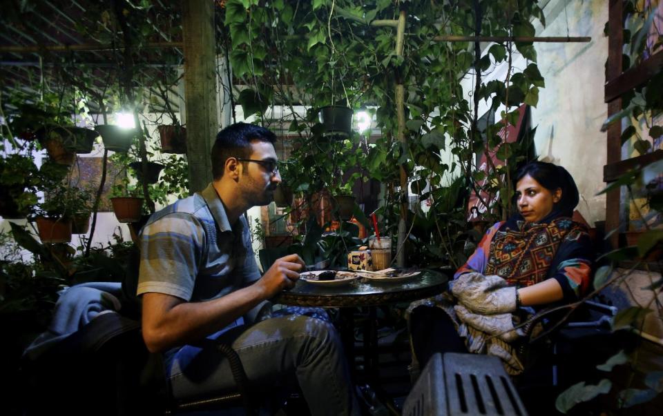 In this Tuesday, March 4, 2014 photo, an Iranian woman meets with her friend at a cafe in Tehran, Iran. For years Iranian authorities kept the number of cafes limited since they were seen as a symbol of Western influence and places to spread non-Islamic beliefs. But reports of cafes being shut because they violate “Islamic dignities” have dropped markedly in recent months, suggesting a growing tolerance by the authorities. (AP Photo/Vahid Salemi)