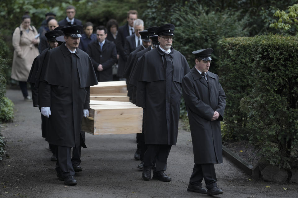 Caskets containing bones found on the grounds of the Freie Universitat, Free University are transported for burial, at the Waldfriedhof in Berlin, Germany, Thursday, March 23, 2023. Thousands of bone fragments found in the grounds of a Berlin university where an institute for anthropology and eugenics was once located, which may include the remains of victims of Nazi crimes, were buried on Thursday. (AP Photo/Markus Schreiber)