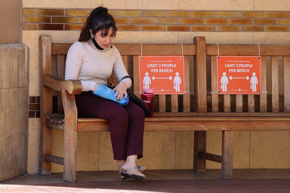 A woman sits on a bench marked for social distancing at the Citadel Outlet mall, as the COVID-19 outbreak continues, in Commerce, California, December 3, 2020. REUTERS/Lucy Nicholson