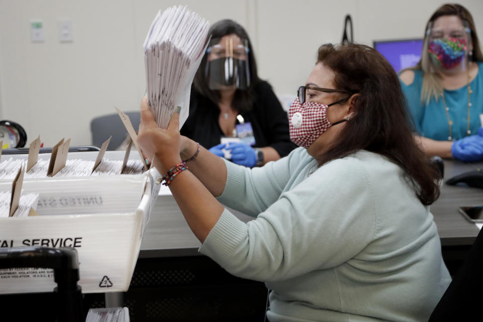 Miami-Dade County Department of Elections employee Elizabeth Prieto gathers vote-by-mail ballots for the August 18 primary election as the canvassing board meets to verify ballot signatures at the Miami-Dade County Elections Department, Thursday, July 30, 2020, in Doral, Fla. President Donald Trump is for the first time publicly floating a "delay" to the Nov. 3 presidential election, as he makes unsubstantiated allegations that increased mail-in voting will result in fraud. (AP Photo/Lynne Sladky)