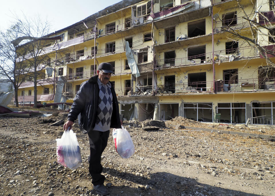 Vovik Zakharian, 72, walks past his apartment building damaged by shelling by Azerbaijan's forces during a military conflict in Shushi, outside Stepanakert, the separatist region of Nagorno-Karabakh, Thursday, Oct. 29, 2020. Fighting over the separatist territory of Nagorno-Karabakh continued on Thursday, as the latest cease-fire agreement brokered by the U.S. failed to halt the flare-up of a decades-old conflict between Armenia and Azerbaijan. (AP Photo)