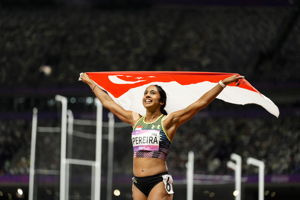 Singapore's Shanti Pereira holds aloft her country's flag after winning the women's 200m final at the 2023 Hangzhou Asian Games. (PHOTO: SNOC/Kong Chong Yew)