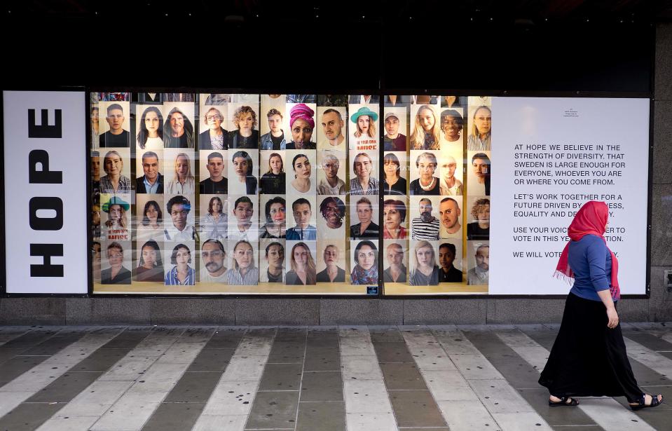 In this Aug. 31, 2018 photo a woman walks by an advertising for diversity and tolerance in the window of shopping mall in Stockholm, Sweden. (AP Photo/Michael Probst)