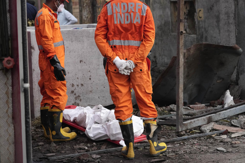 National Disaster Response Force rescuers stand near the dead body of a person after an explosion and fire at a chemical factory in Dombivali near Mumbai, India, Friday, May 24, 2024. Multiple people were killed and dozens were injured in the incident that happened Thursday. (AP Photo/Rajanish Kakade)