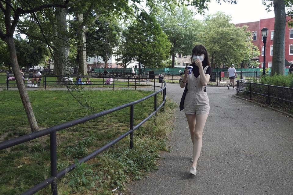 In this June 22, 2020 photo, Marissa Oliver, a COVID-19 survivor who found comfort discussing her experience with the virus and fear of death at Death Cafe meetups, walks through a park in her neighborhood in the Brooklyn borough of New York. Others attending virtual Death Cafes, part of a broader "death-positive" movement to encourage more open discussion about grief, trauma and loss, are coping with deaths from COVID-19, cancer and other illnesses. (AP Photo/Emily Leshner)