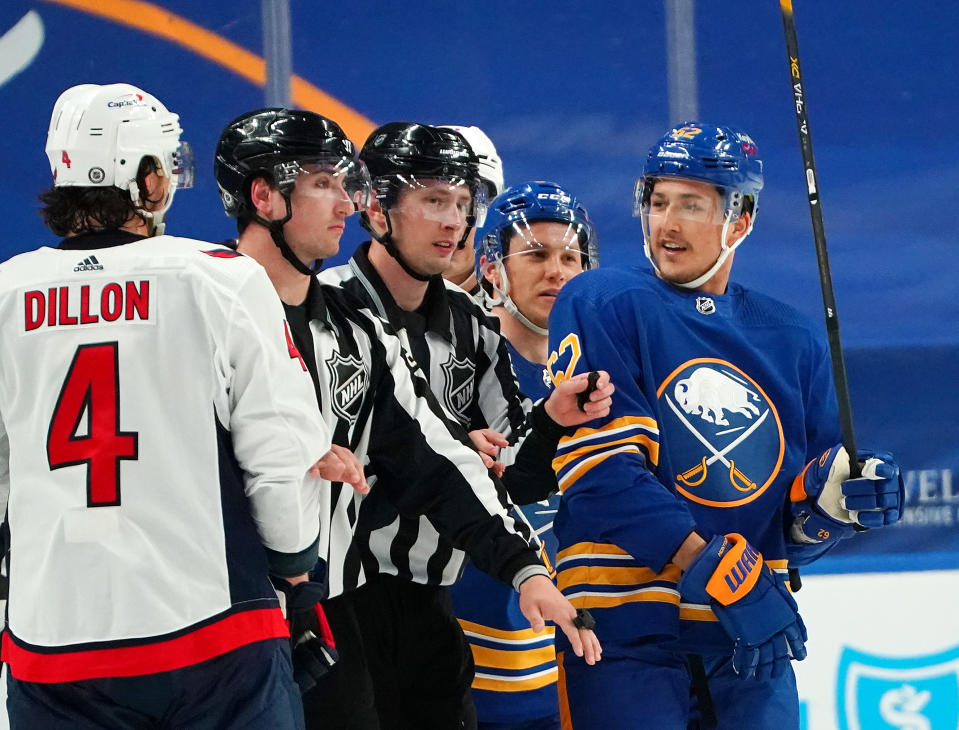 BUFFALO, NY - APRIL 9: The linesman separate Brenden Dillon #4 of the Washington Capitals and Brandon Montour #62 of the Buffalo Sabres during the third period at KeyBank Center on April 9, 2021 in Buffalo, New York. (Photo by Kevin Hoffman/Getty Images)