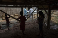 Children watch a government team remove the body of Susana Cifuentes, who died from symptoms related to the new coronavirus at the age of 71, in the Shipibo Indigenous community of Pucallpa, in Peru’s Ucayali region, Monday, Aug. 31, 2020. The Shipibo had tried to prevent COVID-19’s entrance by blocking off roads and isolating themselves. But in May many came down with fevers, coughs, difficulty breathing and headaches. (AP Photo/Rodrigo Abd)