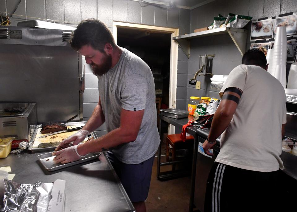 George Mulaj (left), the owner of Texas Cowboy BBQ, and Filippo Comparetto prepare lunch orders Friday.