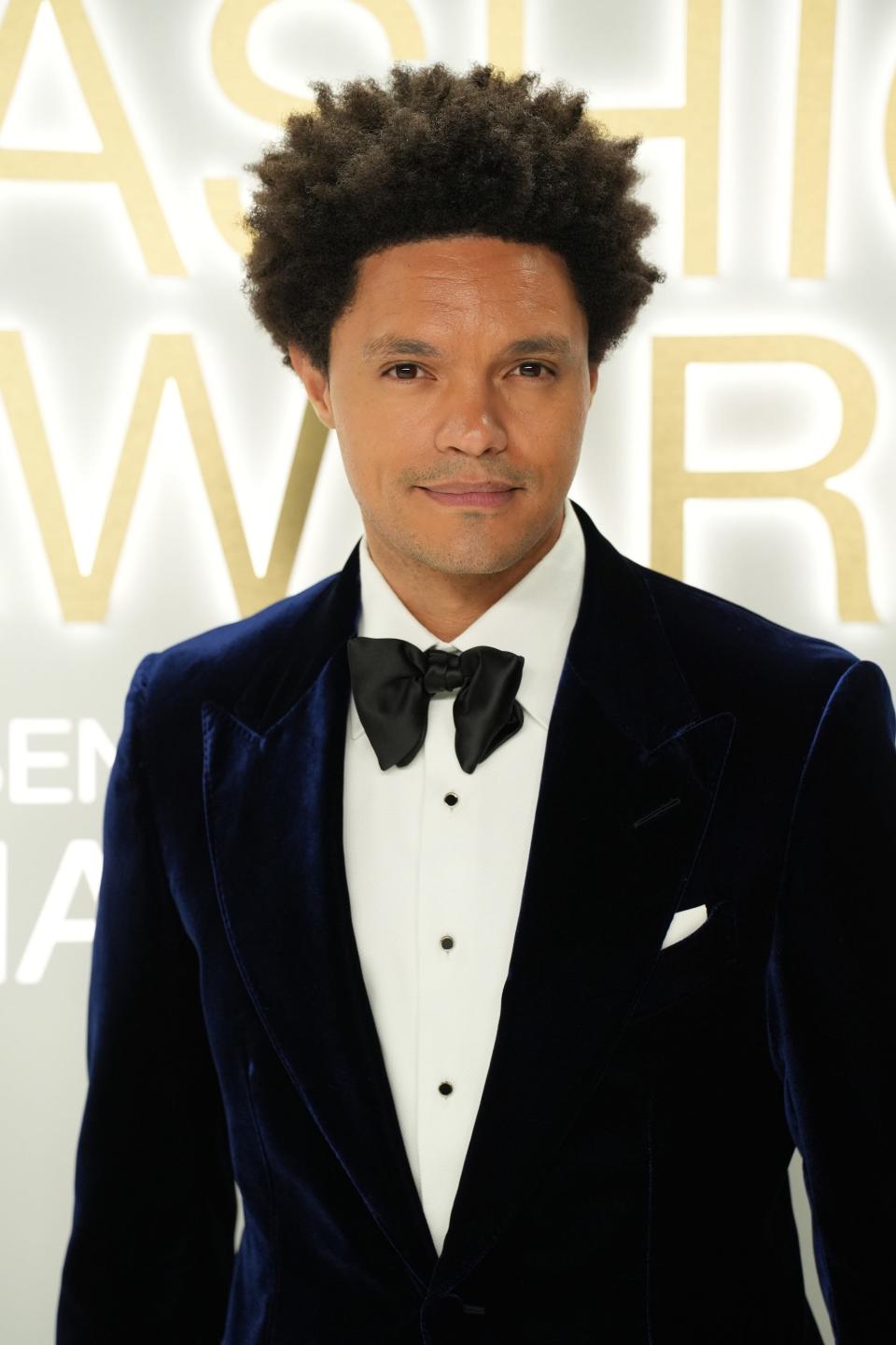 Trevor Noah poses for photos in a blue velvet suit and black bow tie.