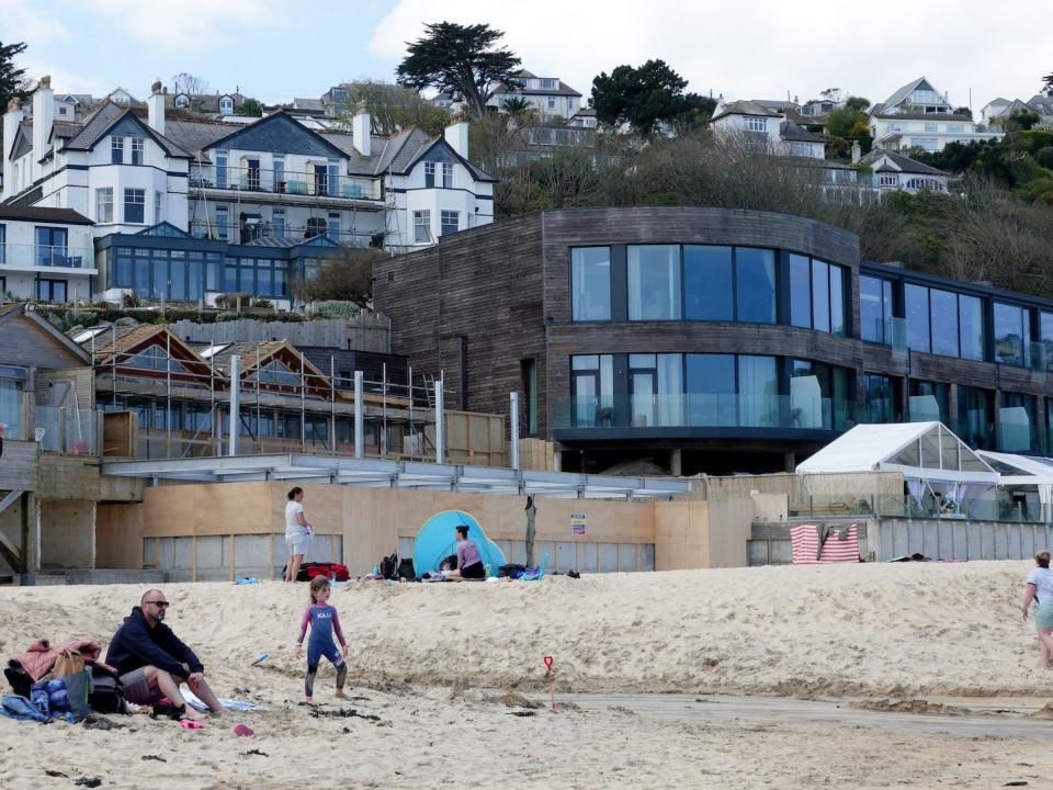 A view of Carbis Bay Hotel's modern and older buildings, with the beach in the foreground.