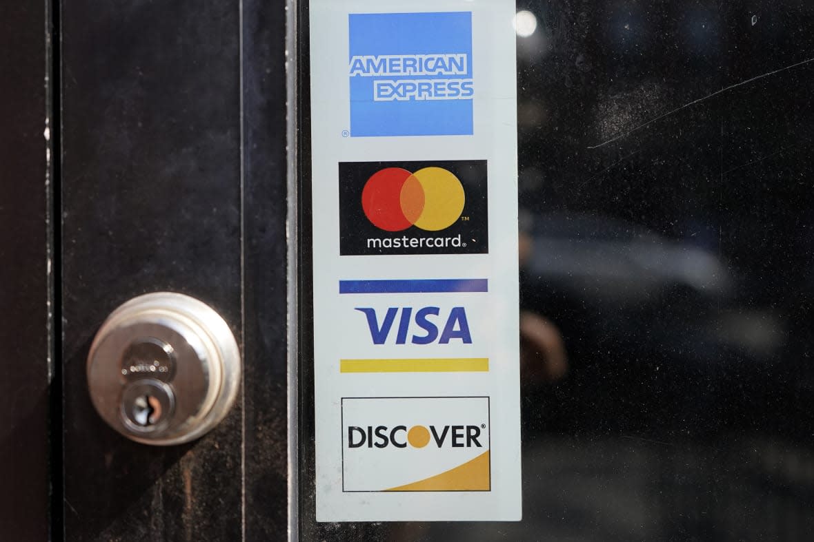 Credit card logos are displayed on a business’s door, Monday, July 5, 2021, in Cambridge, Mass. (AP Photo/Steven Senne, File)