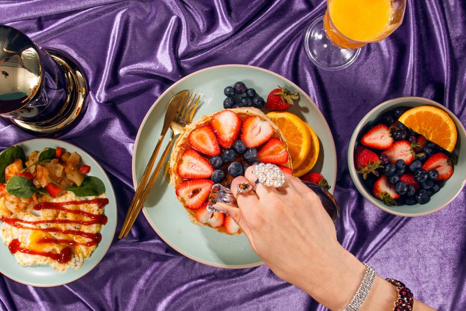 Woman's hand pouring syrup over pancakes