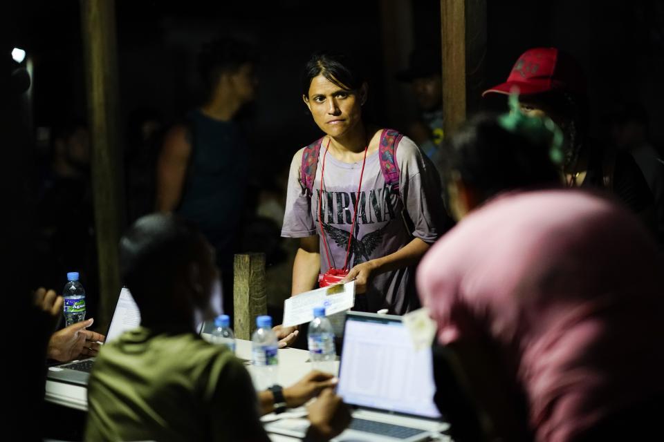 A migrant shows their ID to Panamanian immigration officials upon arrival to Bajo Chiquito, Darien province, Panama, late Wednesday, Oct. 4, 2023, after walking across the Darien Gap from Colombia. (AP Photo/Arnulfo Franco)