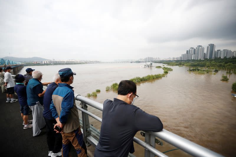 Residents look on a submerged Han River park by flooded Han River in Seoul