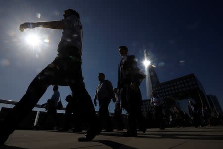 FILE PHOTO: Workers cross London Bridge with the Shard skyscraper seen behind during the morning rush hour in London, Britain, June 13, 2017. REUTERS/Toby Melville