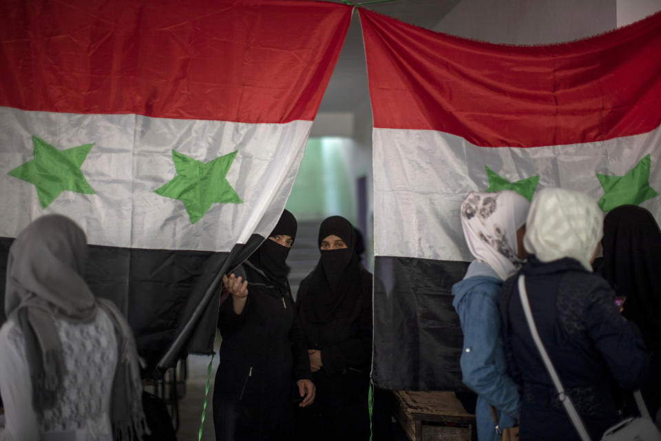 Syrian women vote during a presidential election, at a polling station in the town of Douma, near the Syrian capital Damascus, Syria, Wednesday, May 26, 2021. Syrians headed to polling stations early Wednesday to vote in the second presidential elections since the deadly conflict began in the Arab country. (AP Photo/Hassan Ammar)