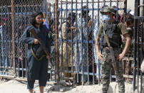 FILE - A Pakistani paramilitary soldier, right, and a Taliban fighter stand guard on their respective sides at a border crossing point between Pakistan and Afghanistan, in Torkham, in the Khyber district of Pakistan, Aug. 21, 2021. Faced with rising violence, Pakistan is taking a tougher line to pressure Afghanistan’s Taliban rulers to crack down on militants hiding on their soil, but so far the Taliban remain reluctant to take action -- trying instead to broker a peace. (AP Photo/Muhammad Sajjad, File)