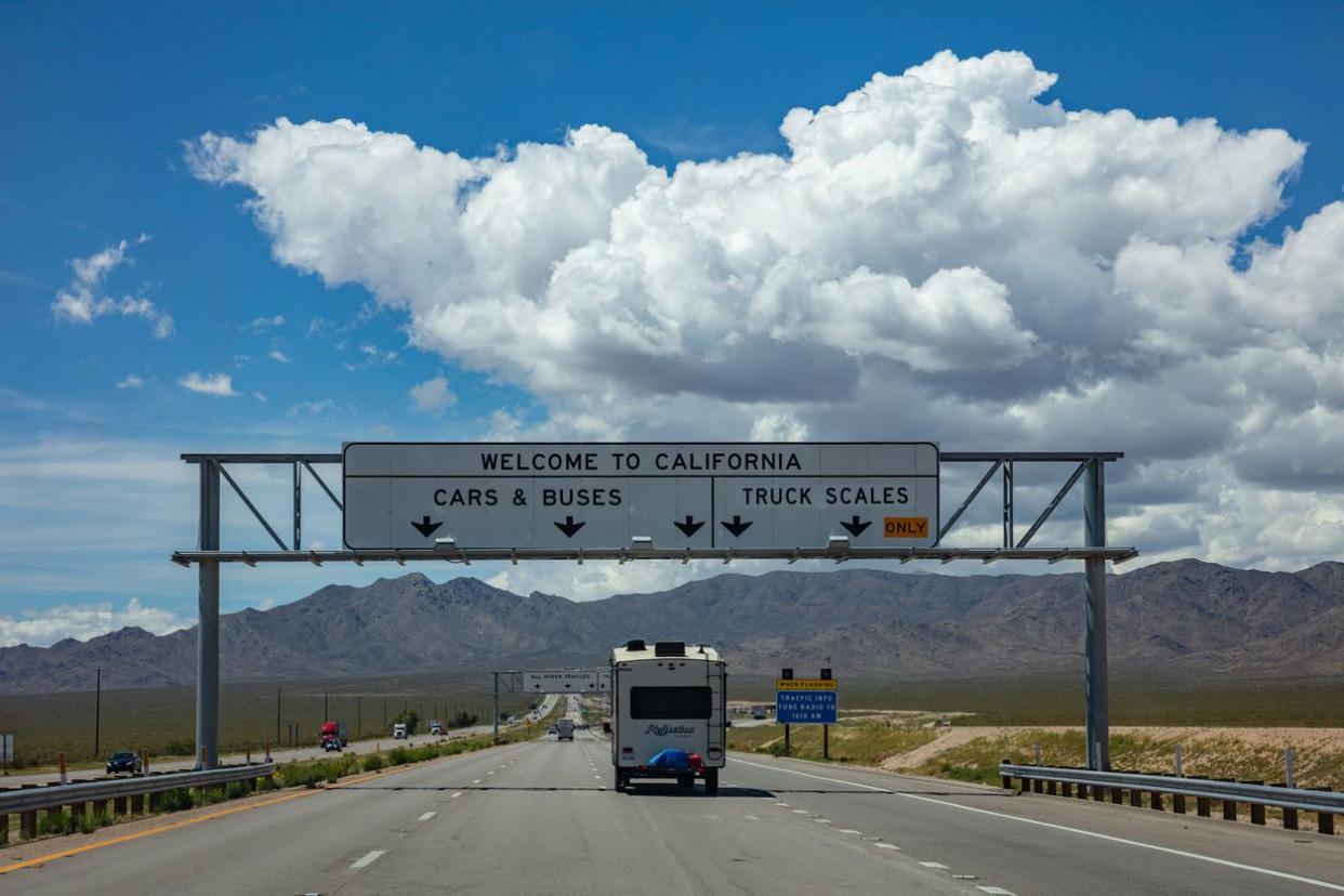 Welcome to California road sign billboard on the highway, blue cloudy sky, motorhome driving