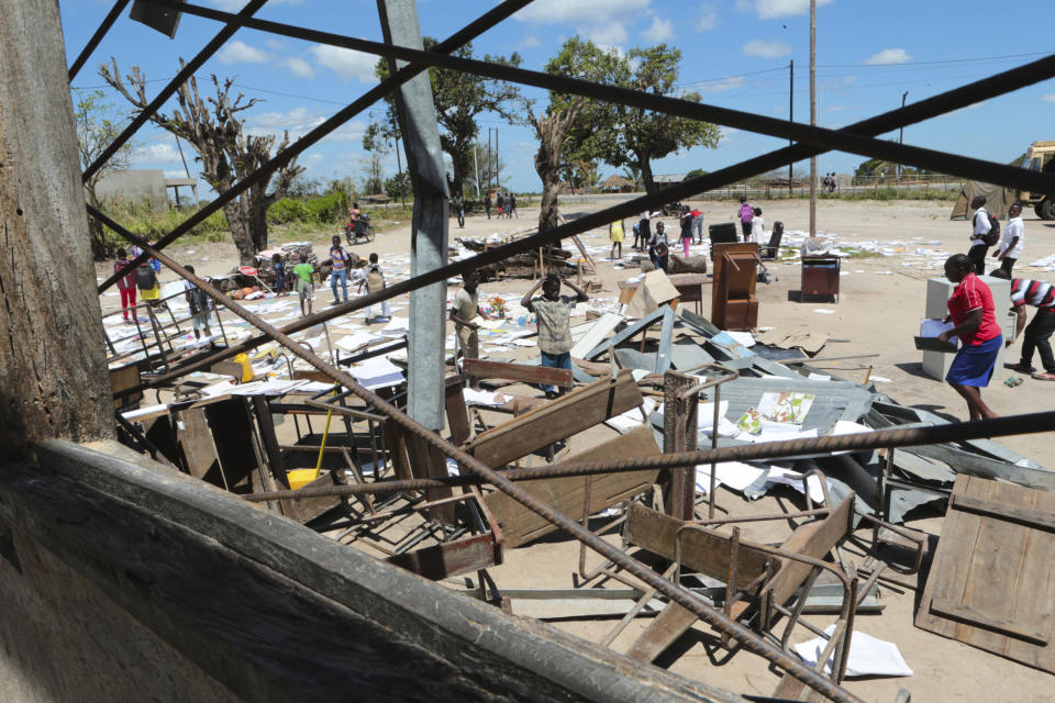 Schoolchildren pick up books that were left to dry in the sun after their school was damaged by Cyclone Idai, in Inchope Mozambique, Monday March 25, 2019. Cyclone Idai's death toll has risen above 750 in the three southern African countries hit 10 days ago by the storm, as workers rush to restore electricity, water and try to prevent outbreak of cholera. (AP Photo/Tsvangirayi Mukwazhi)