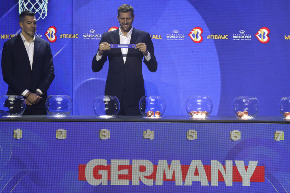 German former basketball player and NBA star Dirk Nowitzki, right, shows the ticket for Gernany national basketball team during the FIBA World Cup 2023 draw in Quezon city, Philippines on Saturday April 29, 2023. (AP Photo/Josefino de Guzman)