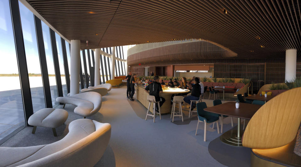 Virgin Galactic employees gather at the coffee bar that serves as the heart of the company's social hub where they will meet with customers and their families at Spaceport America once commercial operations begin near Upham, New Mexico, on Thursday, Aug. 15, 2019. Virgin Galactic unveiled some of the interior spaces of the custom-tailored terminal Thursday, saying the designs are aimed at connecting the customers with operations as they prepare for their suborbital flights. (AP Photos/Susan Montoya Bryan)