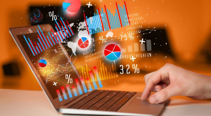 best investments: a hand using the touchpad on a laptop. a concept image of figures and charts is emerging from the laptop screen.