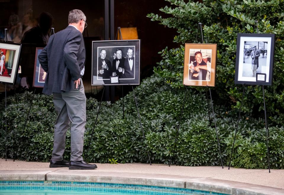 A guest looks at photos of American film and dance star Gene Kelly during a party held in his honor at Frank Sinatra's Twin Palms estate in Palm Springs, Calif., Saturday, Feb. 26, 2022.