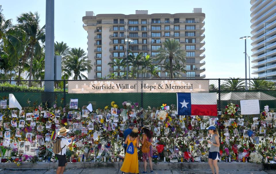 The Champlain Towers South condominium is visible behind the memorial wall for people missing in the collapse of the building in Surfside Florida.
