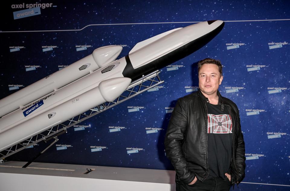 Elon Musk in a leather jacket poses on the red carpet of the Axel Springer Awards