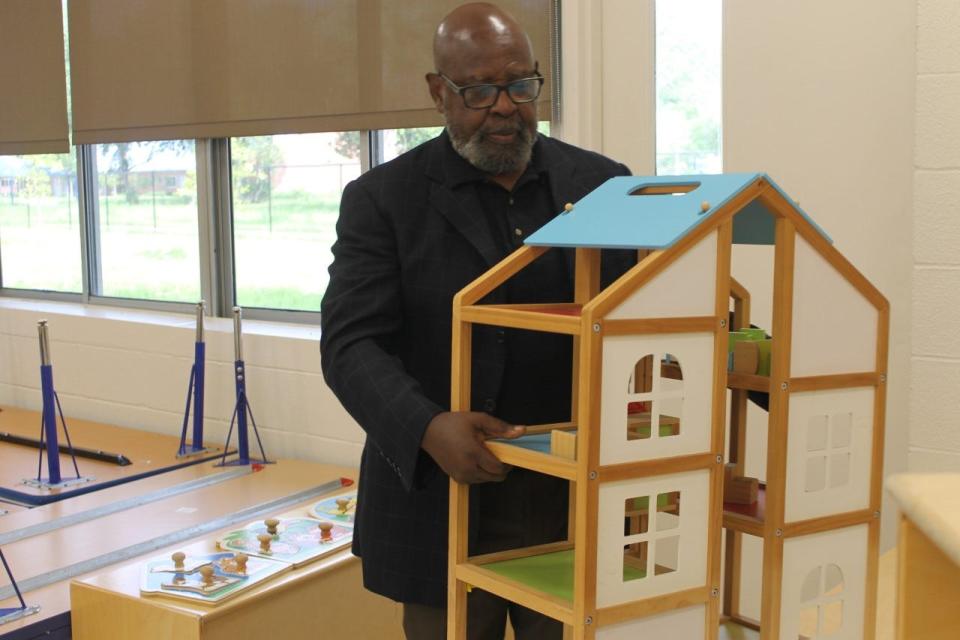 James F. Lawrence, director of Gainesville For ALL, places a toy house on a table in preparation for the opening of the Gainesville Empowerment Zone Family Learning Center