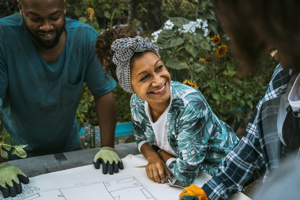 Two people smiling and discussing over a paper, possibly planning a garden