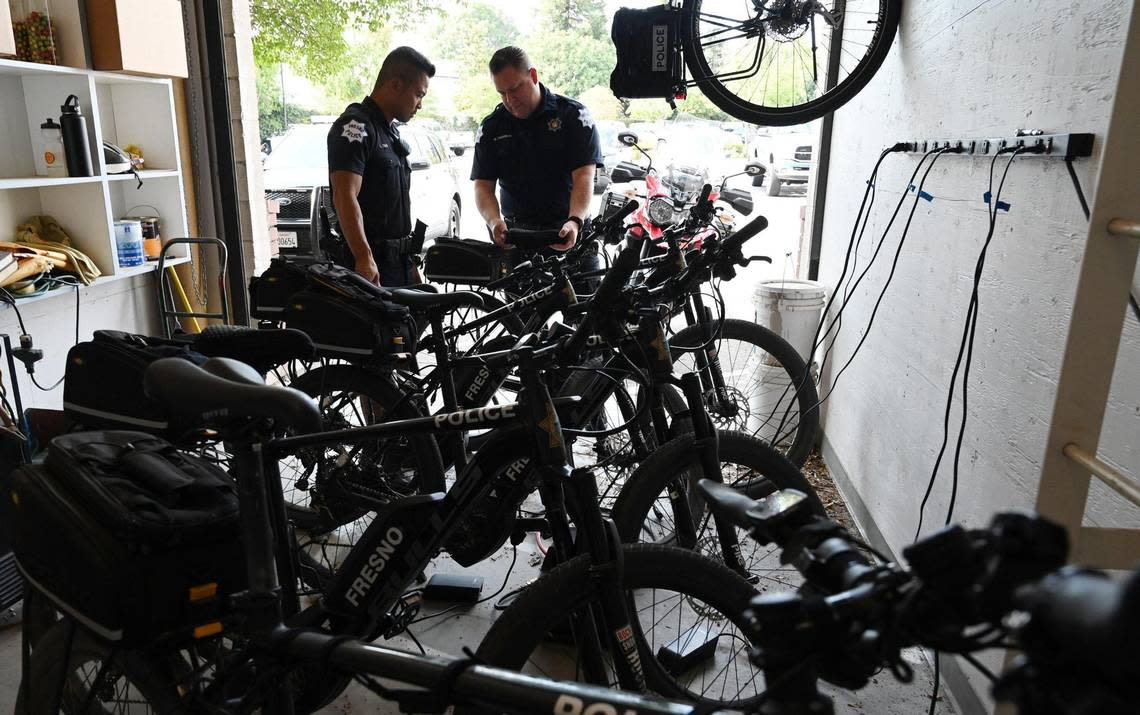 Fresno police officers Luke Tran, left, and Dustin Freeman, right, pull their electric-assist bikes from storage as they prepare for their patrol of River Park Saturday afternoon, July 30, 2022 in Fresno.