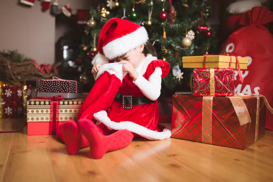 young girl sit on floor and looking for gift from big sock