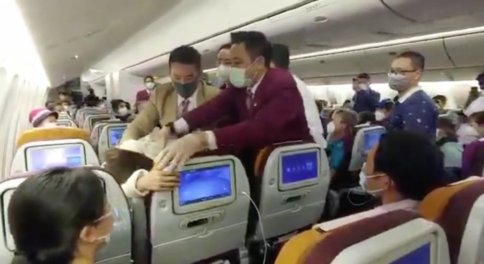 Thai Airways staff restrain a passenger.