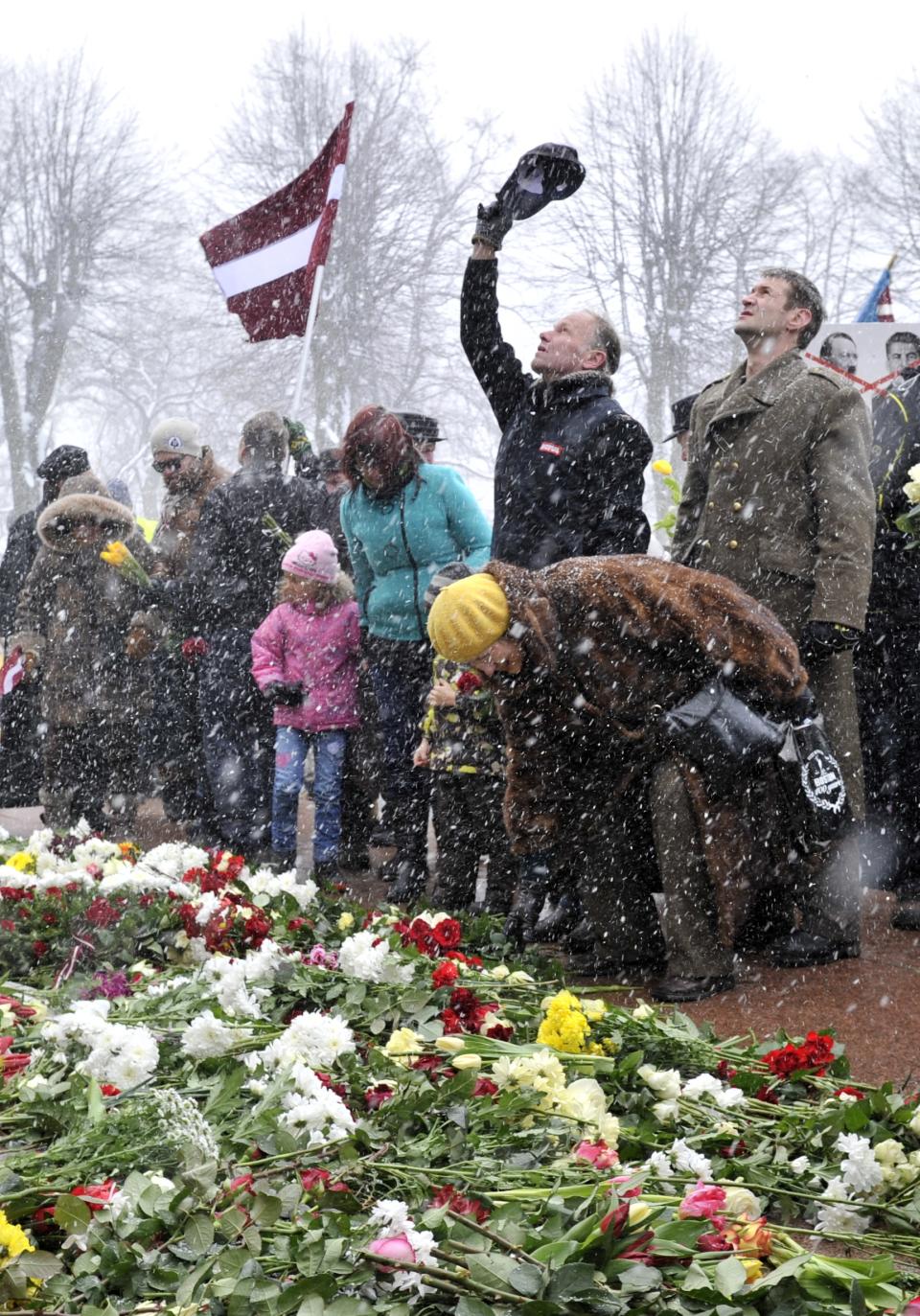 People put flowers at the Freedom Monument to commemorate World War II veterans who fought in Waffen SS divisions, in Riga, Latvia, Sunday, March 16, 2014. People participate in annual commemorations of Latvian soldiers who fought in Nazi units during WWII. (AP Photo/Roman Kosarov, F64 Photo Agency)