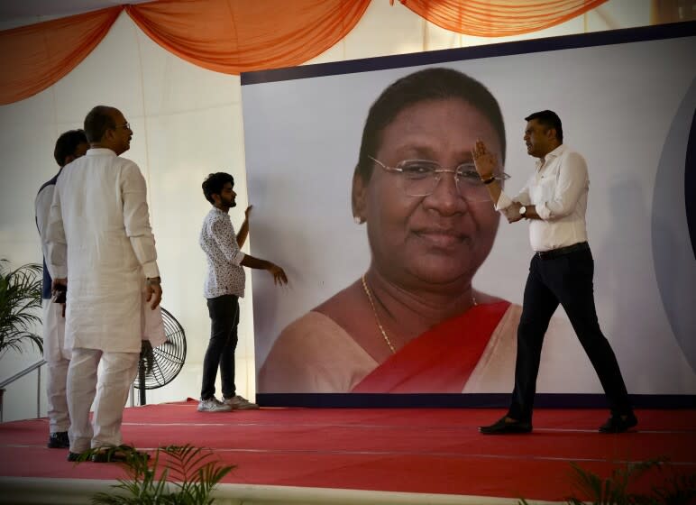 Workers put up a giant hoarding of Droupadi Murmu for her felicitation, before she was announced as the country's new President, in New Delhi, India, Thursday, July 21, 2022. Murmu, who hails from a minority ethnic community, was chosen Thursday as India's new president, a largely ceremonial position. (AP Photo/Manish Swarup)