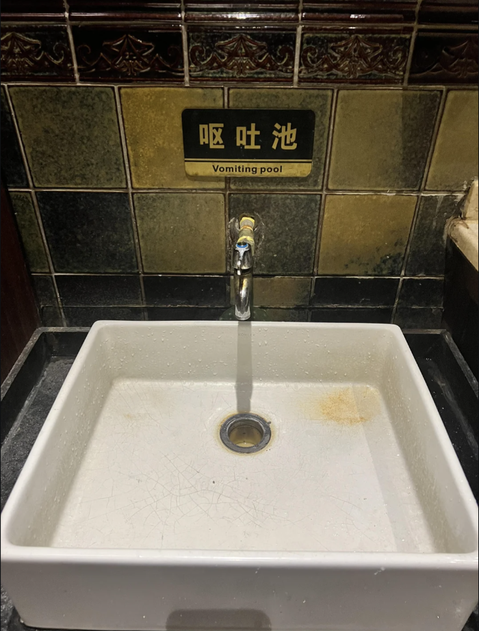 A sink with a sign above labeled "Vomiting pool" in English and Chinese