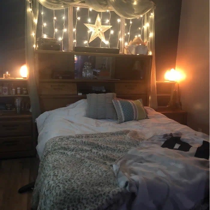 Reviewer's photo of the curtain fairy lights used as a headboard for a bed