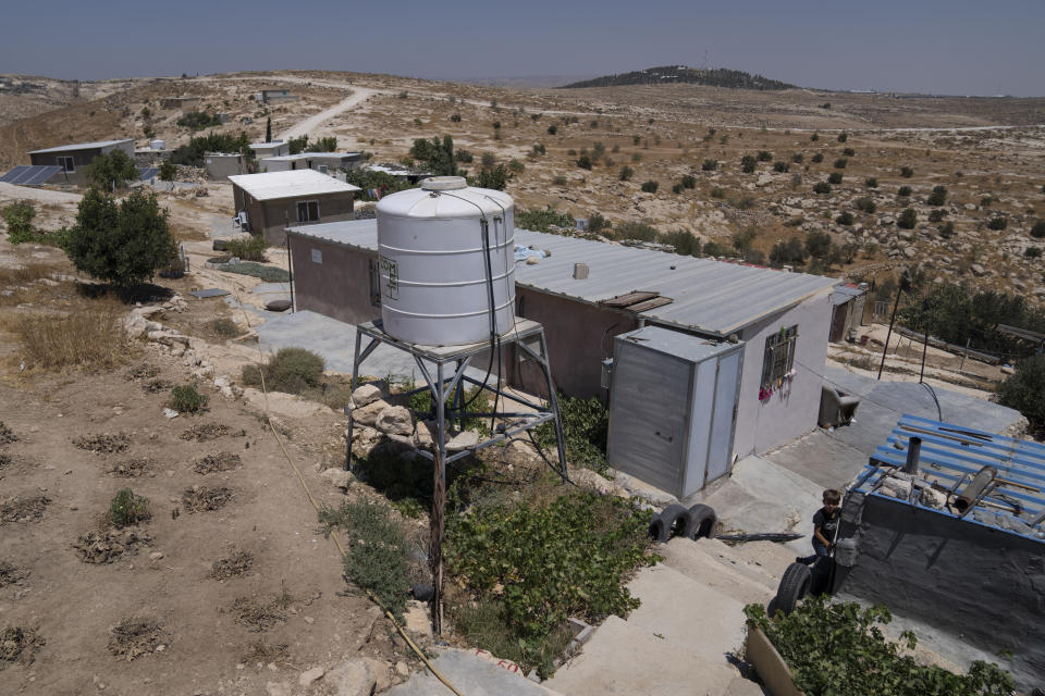 A boy plays by the family house, at the Palestinian hamlet of Khallat al-Dhaba, in the cluster of Bedouin communities in Masafer Yatta, West Bank, Monday, Aug. 1, 2022. Palestinians living in Masafer Yatta, in the occupied West Bank, fear they could be expelled at any time after Israel's Supreme Court ruled in favor of the military earlier this year in a two-decade legal battle. (AP Photo/Nasser Nasser)