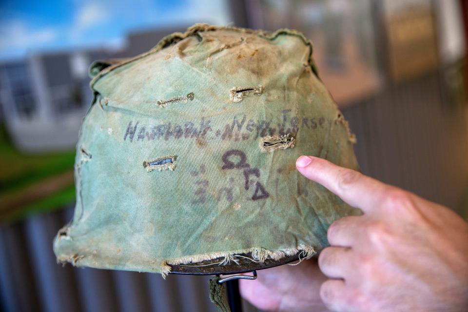 Mike Thornton, curator and interim executive director, talks about a helmet cover worn by Lance Cpl. William "Billy" Dutches, the first soldier from Hawthorne to be killed in the Vietnam War, which is displayed in the special exhibition, There and Back: The Journey to Vietnam and Home, at the Vietnam Era Museum and Education Center in Holmdel, NJ Thursday, November 3, 2022.  Hawthorne, New Jersey and three Greek letters are written on the side of the cover.