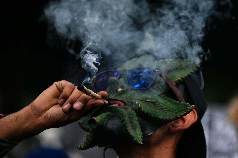April 20, 2023: A man wearing a mask with the figure of a marijuana leaf smokes a joint during the International Marijuana Day celebration at Paseo de la Reforma Avenue in Mexico City.